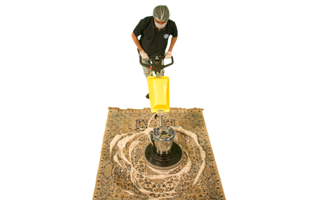 a cleaner cleaning a carpet using a yellow single disk machine with lots of lather being rubbed into the carpet by the machine brush