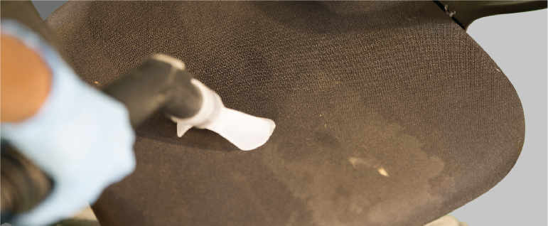 Vacuuming of an office chair by a cleaner to extract dust from the chair upholstery