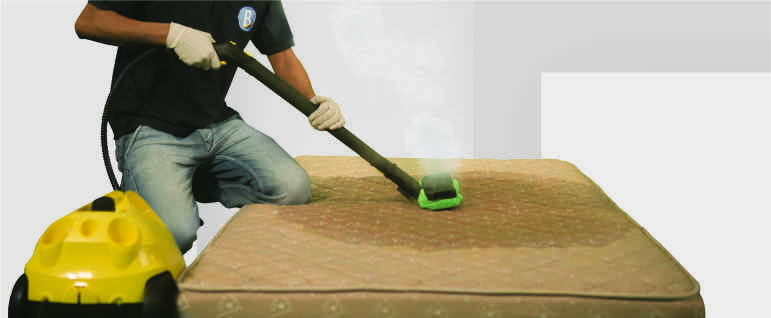 A hotel cleaner sanitizing a mattress using a steam cleaning machine